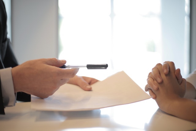 Cropped person handing a pen and documents to someone else
