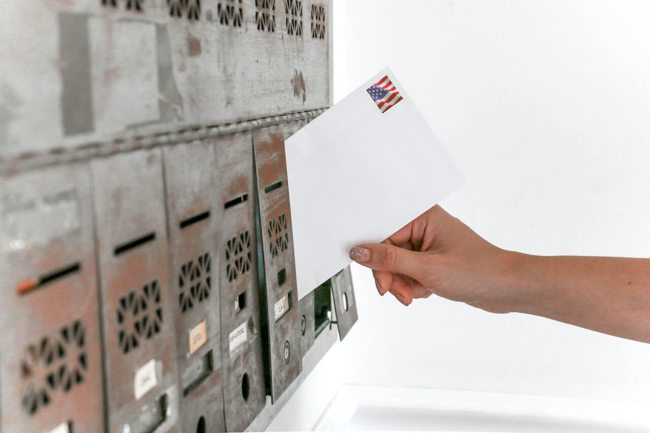 Envelope being slid into gray metal mailbox
