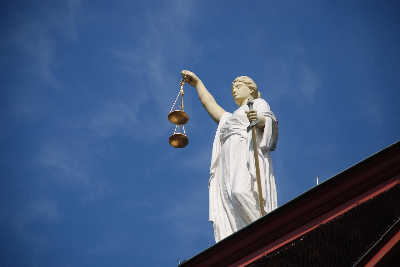 Statue of Lady Justice holding scales and a sword against a clear sky