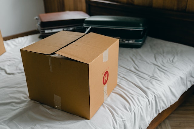 a packed box and two suitcases sitting on a bed