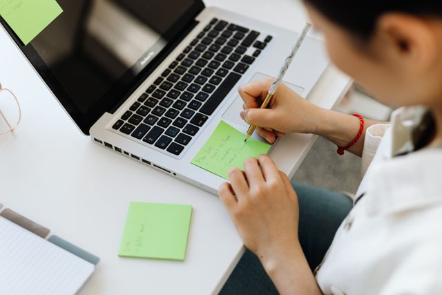 person writing notes on a laptop