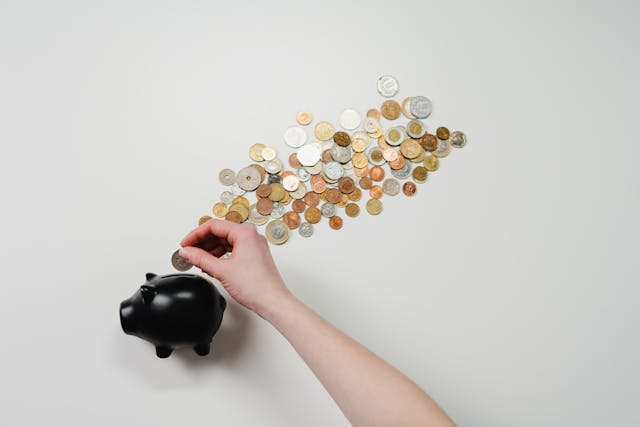 someone putting coins into a black piggy bank