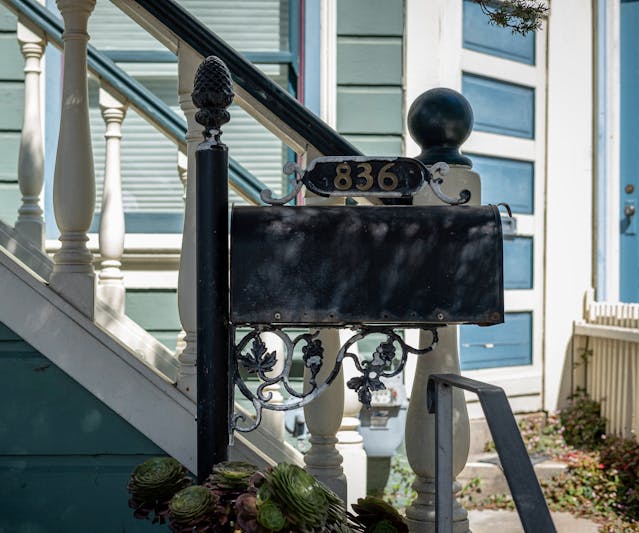 a mailbox in front of a front door staircase with a railing