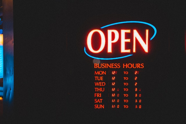 open sign with business hours underneath