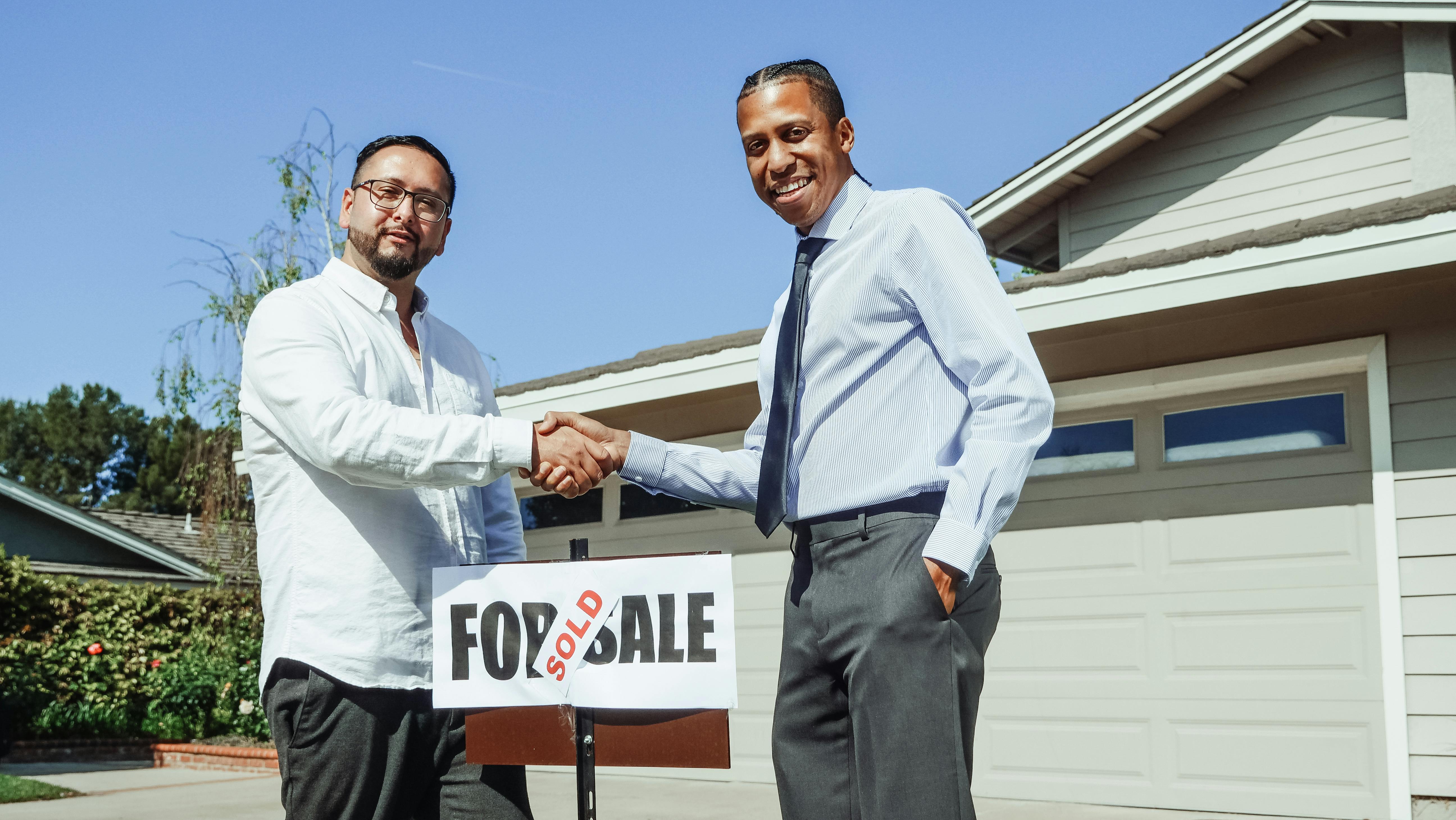 two people shaking hands in front of a sign that says 