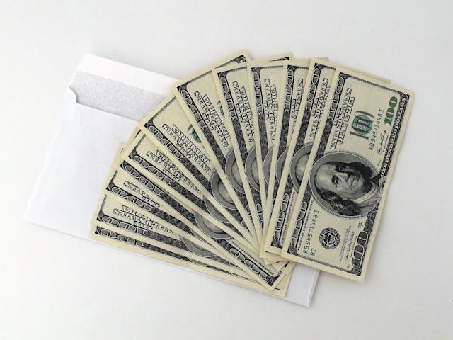 cash fanned out over a white envelope